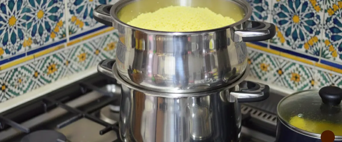 Steaming couscous in traditional couscoussier pot with vegetables